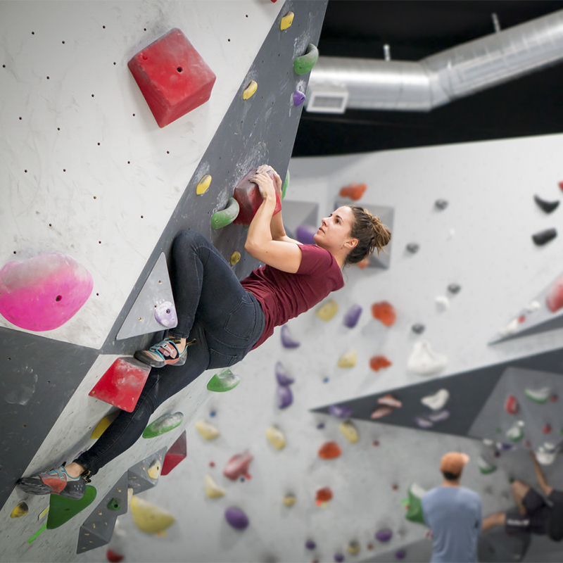 A woman climber on a boulder problem at Vital Climbing Gym