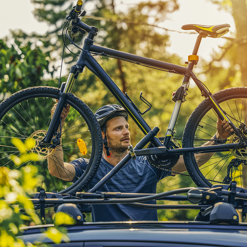 A man positions his bike on a rooftop bike rack 