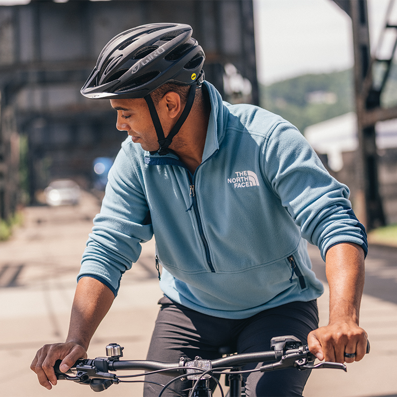 Male cyclist riding a bike wearing a blue The North Face shirt