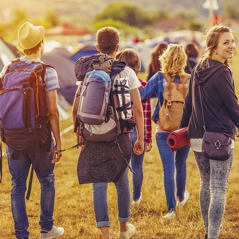 A group of festival-goers walk along tents in a camp